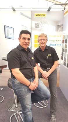 Zwei Mitarbeiter beraten an einem Weru-Messestand zu Fenstern, Energieeffizienz und Komfort.