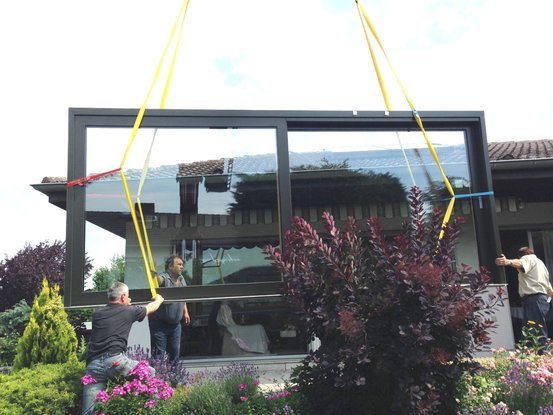 Handwerker montieren ein großes Panoramafenster in ein modernes Einfamilienhaus.