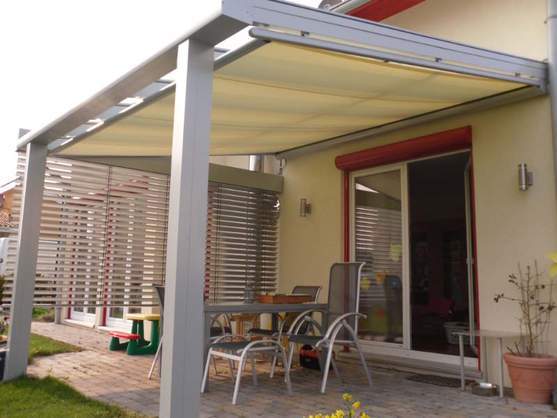 Terrassenüberdachung aus Aluminium mit Sonnenschutz und Gartenmöbeln auf Terrasse.